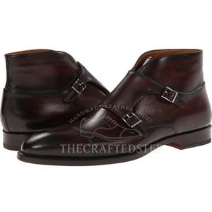May include: Dark burgundy leather ankle boots with double buckle fastenings. The boots have a polished finish and a classic design, suitable for formal or semi-formal occasions. The text "HANDMADE LEATHER SHOES" and "THECRAFTEDSTEP" are visible.