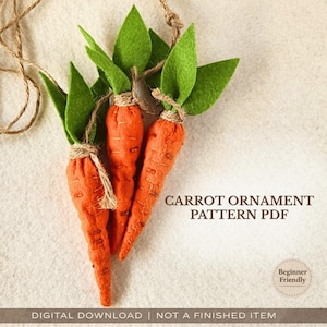 Op de afbeelding: Drie handgemaakte oranje wortelornamenten met groene viltbladeren, vastgebonden met touw. De tekst "CARROT ORNAMENT PATTERN PDF" is zichtbaar. De woorden "Beginner Friendly" zijn ook zichtbaar.