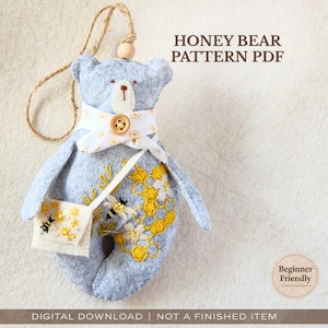 May include: A light blue felt bear with a white scarf and a small purse. The bear has embroidered yellow honeycomb and bee details. The text "HONEY BEAR PATTERN PDF" is visible. The words "Beginner Friendly" and "DIGITAL DOWNLOAD | NOT A FINISHED ITEM" are also present.