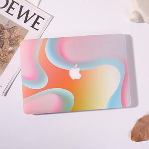 May include: A laptop hard shell case featuring a vibrant, abstract gradient design with flowing, organic shapes in shades of orange, pink, yellow, and light blue. The centre of the case displays a cutout for the white Apple logo.