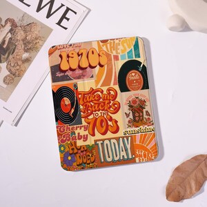 May include: A retro-themed tablet case with a collage of 1970s-inspired graphics. The design features a record player, vinyl records, flowers, and the text "Take me back to the 70s." The color palette includes orange, yellow, and brown.