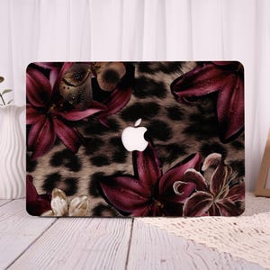 May include: A laptop case featuring a floral and leopard print design. The case has a dark background with burgundy flowers and a leopard print pattern. The Apple logo is visible in the center.