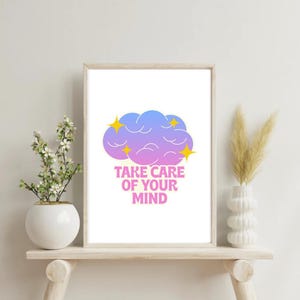 May include: A framed print with the text "TAKE CARE OF YOUR MIND" in pink. The artwork features a cloud in shades of blue and purple with yellow star accents. The print is displayed on a wooden shelf with decorative vases.