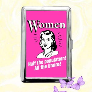May include: A silver metal cigarette case with a bright pink insert. The insert features a retro illustration of a woman and the text "Women Half the population! All the brains!" Several purple butterflies are scattered around the case.