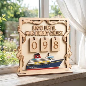 May include: A light-coloured wooden countdown sign with the text "DAYS UNTIL OUR DISNEY CRUISE" and three hanging rectangular tiles displaying the number 098. A layered wooden cruise ship graphic with the text "See Ya Soon!" is attached below.