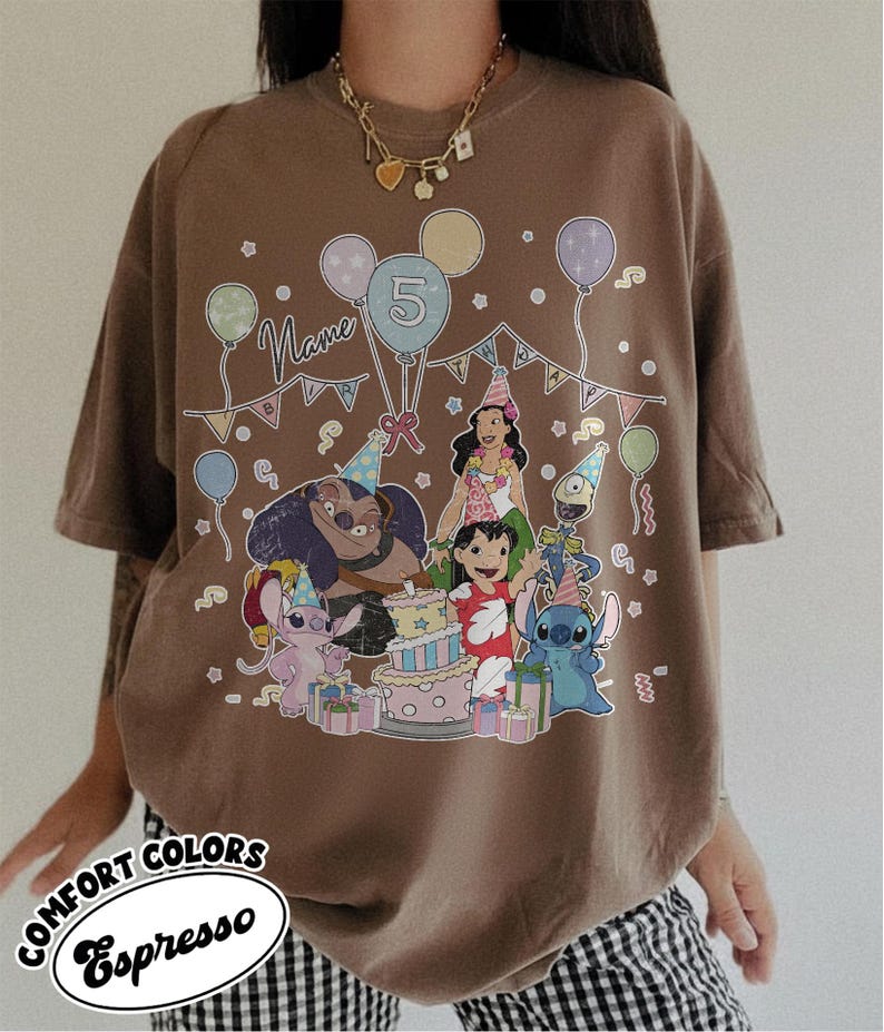 May include: Brown t-shirt featuring a colorful graphic of cartoon characters, balloons, and a birthday cake. The design includes the number 5 and the word "Name". The shirt has the words "Comfort Colors Espresso" in a circular design.