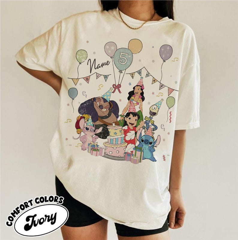 May include: Ivory Comfort Colors t-shirt featuring a colorful birthday party design with cartoon characters, balloons, and a cake. The design includes the number 5 and the word "Name". The shirt is a relaxed fit.