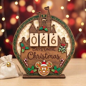 May include: A circular wooden countdown calendar featuring a castle silhouette, three light-colored wooden number tiles displaying 066, and the text "DAYS UNTIL Christmas". It is decorated with holly, mistletoe, candy canes, and a gingerbread mouse.