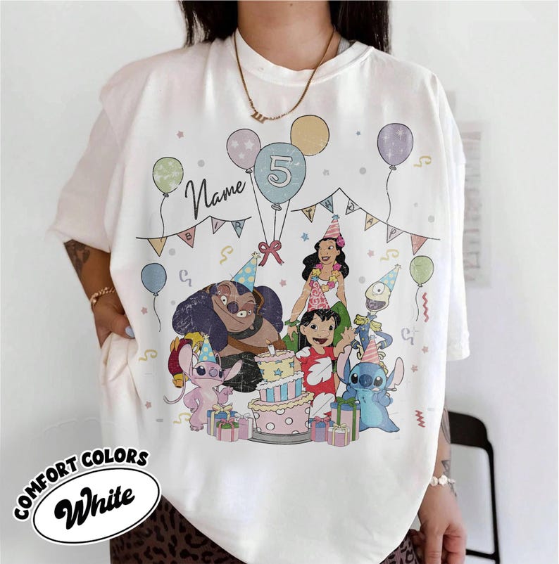 May include: White Comfort Colors t-shirt featuring a colorful graphic of characters from a popular animated movie celebrating a birthday. The design includes balloons, a cake, and the number 5.