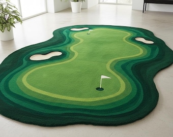 May include: An irregularly shaped area rug featuring a golf course design with various shades of green representing the fairway and rough, along with beige sand bunkers and two white flagsticks placed in holes on the green surface.