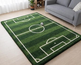 Puede incluir: Una alfombra rectangular con diseño de campo de fútbol verde, líneas blancas, círculo central y áreas de penalti. La alfombra tiene una superficie texturizada con rayas alternas de color verde claro y oscuro y un pequeño gráfico de balón.
