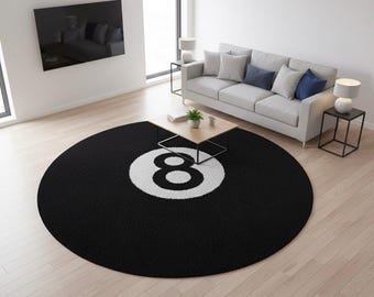Puede incluir: Una alfombra redonda negra con un diseño blanco del número ocho. La alfombra está en un salón con un sofá, una mesa de centro y un televisor montado en la pared. El diámetro de la alfombra es de aproximadamente 213 cm.