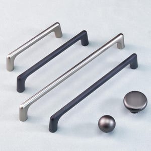May include: A selection of cabinet hardware, featuring two silver and two dark grey bar pulls, and two knobs. The pulls are approximately 20 cm long. The knobs are round with a matte finish. All hardware is made of metal.