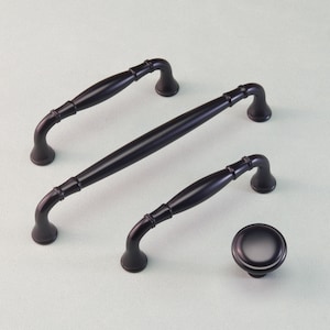 May include: A collection of black cabinet hardware, featuring two handles, a longer pull, and a knob. The handles and pull have a curved design with decorative detailing. The knob is round with a slightly raised centre.