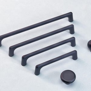 May include: A selection of black cabinet handles and knobs. There are four bar handles of varying lengths and two knobs, one spherical and one disc-shaped. The handles and knobs are all a matte black finish.