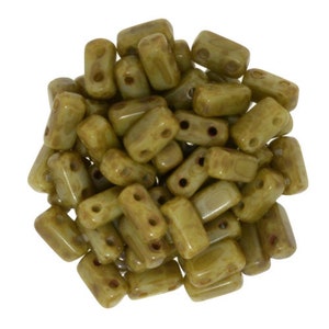 May include: A pile of green glass beads with two holes in each bead. The beads are rectangular in shape and have a mottled, textured surface.