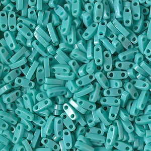May include: A close-up of a large quantity of turquoise blue plastic beads. The beads are rectangular with two holes on each end.