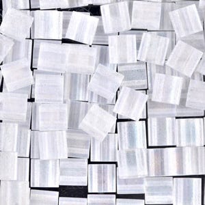 May include: A collection of small, white, iridescent square tiles. The tiles have a subtle striped pattern and are arranged in a random pattern.