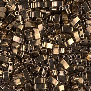 May include: A close-up view of a large quantity of gold-colored rectangular seed beads. The beads have two holes on each side and are arranged in a random pattern.