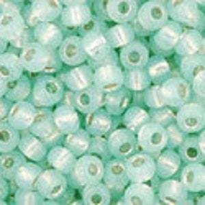 May include: A close-up view of a large quantity of small, round, light blue glass beads. The beads have a subtle iridescent sheen.