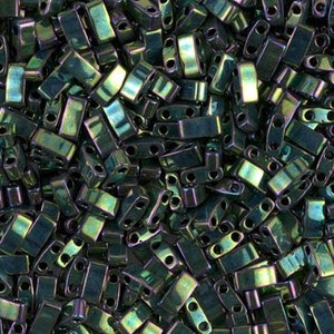 May include: A close-up view of a large quantity of dark green iridescent glass seed beads. The beads are rectangular in shape with two holes on each side.