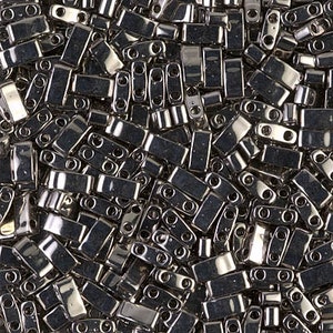 May include: A bulk pack of silver-toned, rectangular glass beads with two holes each. The beads are arranged in a random pattern, showcasing their reflective surface.