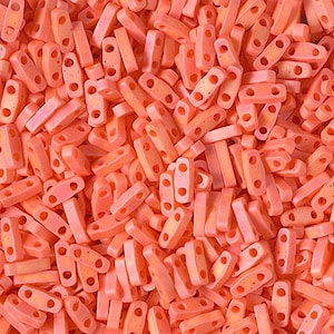 May include: A large pile of small, bright orange plastic beads with two holes in each bead. The beads are all the same size and shape.