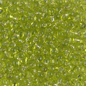 Può includere: Un'immagine ravvicinata di una grande quantità di piccole perline rotonde in vetro verde lime. Le perline hanno una finitura lucida e iridescente.