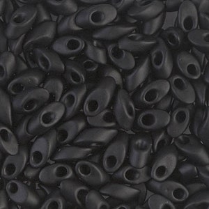 May include: A close-up of a pile of black oval-shaped beads with a small hole in the center of each bead.