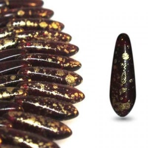 May include: A close-up of a group of dark red glass beads with gold flecks. The beads are shaped like teardrops and are arranged in a row.