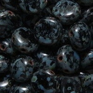 May include: A close-up of a pile of dark blue and black speckled oval beads. The beads have a smooth, polished finish.