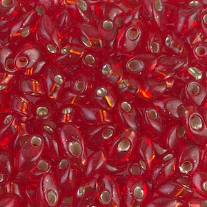 May include: A close-up of a pile of red glass seed beads with silver-toned holes. The beads are shaped like teardrops and have a slightly iridescent finish.