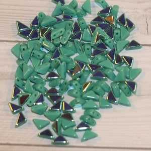 May include: A large quantity of small, triangular, turquoise-colored glass beads with silver accents. The beads have two holes each.