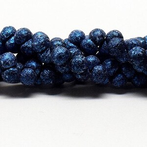 May include: A strand of dark blue round beads with a textured surface.