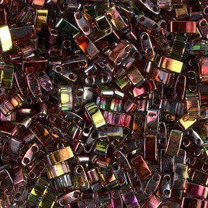 May include: A collection of small, iridescent glass beads in shades of brown, purple, and gold. The beads are rectangular in shape with two holes at each end.