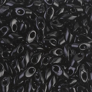 May include: A close-up image of a pile of black glass seed beads. The beads are shaped like a teardrop with a small hole at the top.