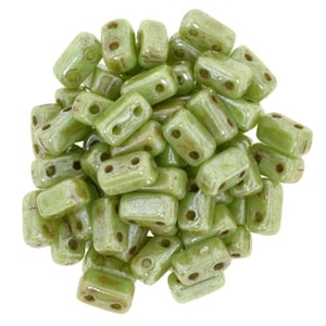 May include: A pile of light green glass beads with a subtle shimmer. The beads are rectangular with two holes in each bead.