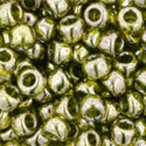 Könnte beinhalten: Nahaufnahme einer großen Menge kleiner, runder, grüner Glasperlen mit einem metallischen Schimmer.