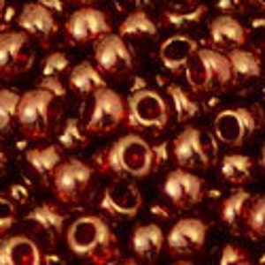 May include: A close-up image of a pile of small, round, copper-colored beads. The beads have a shiny, metallic finish.