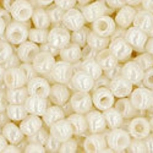 May include: A close-up image of a pile of white seed beads. The beads are small and round, with a slight pearlescent sheen.
