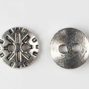 May include: Two silver-colored buttons. One button has a decorative sunburst design with two holes for sewing. The other button is plain with two holes. Both buttons are round and have a slightly aged appearance.