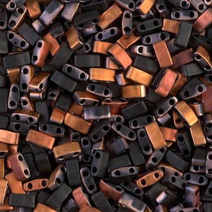 May include: A close-up of a pile of small, rectangular beads in black and copper tones. The beads have two holes in each, and they are arranged in a random pattern.