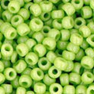 May include: A close-up image of a large quantity of small, round, light green beads. The beads are opaque and have a slightly shiny finish.