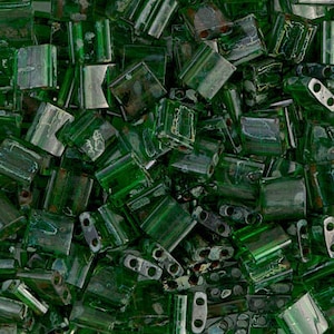 Puede incluir: Primer plano de un montón de cuentas de vidrio verde. Las cuentas son cuadradas y rectangulares y tienen un acabado ligeramente iridiscente.