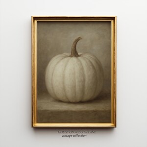 May include: A framed print of a white pumpkin with a brown stem. The pumpkin is set against a muted background. The frame is gold. The text "HOUSE ON WILLOW LANE vintage collection" is at the bottom.