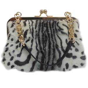 May include: A clutch purse with a gold-tone clasp and chain strap. The purse features a faux fur exterior with a black and white spotted and striped pattern. The black handle is attached to the chain strap.