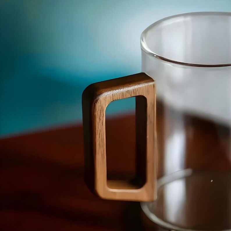 Pode incluir: Uma caneca de vidro transparente com uma pega retangular de madeira. A pega &eacute; de cor castanha quente e est&aacute; presa &agrave; lateral da caneca. A caneca est&aacute; vazia e parece ser feita de vidro transparente.