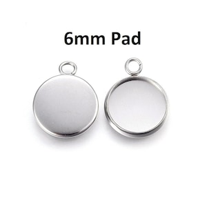 May include: Two silver 6mm round pendant trays with a jump ring at the top. One tray is flat and the other has a raised edge.