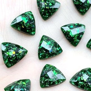 May include: Assortment of 15 green triangle-shaped rhinestones with glitter embedded in the resin.