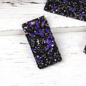 Peut inclure: Trois pinces à cheveux rectangulaires noires avec des paillettes violettes et irisées.